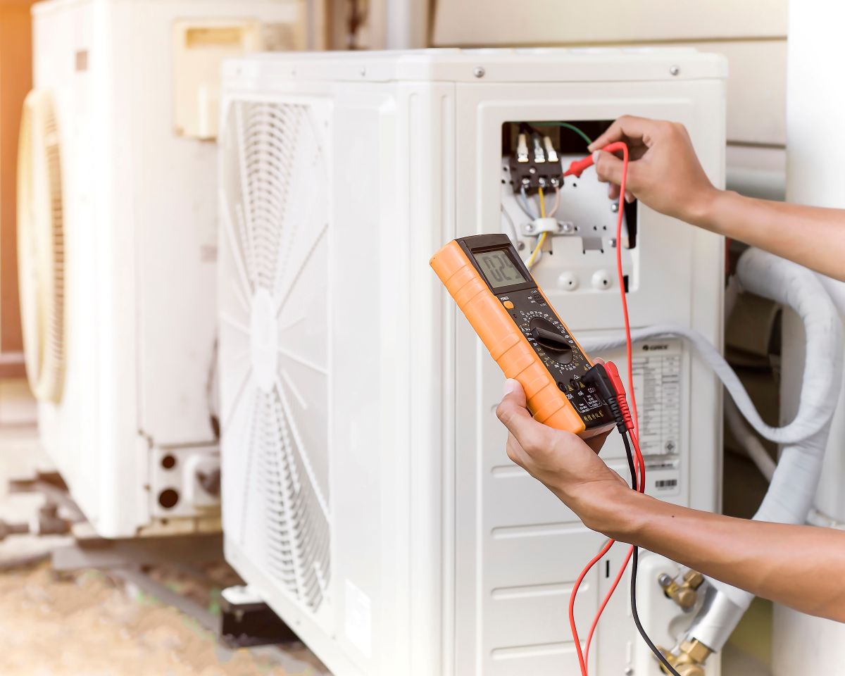 Air conditioner repairman using electricity meter to check air conditioner operation, maintenance concept